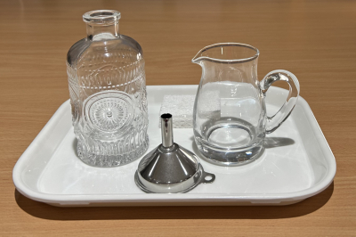 Montessori pouring activity with glass creamer, decanter, and stainless steel funnel